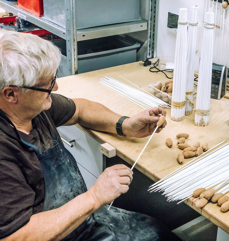 A Rohema craftsman fitting handles to baton shafts